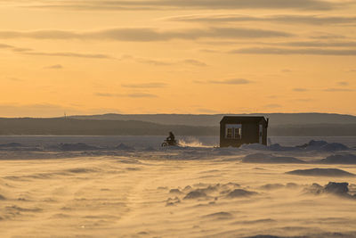 Motocrosso on frozen lake against sky during sunset