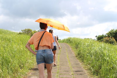 Rear view of woman walking on dirt road