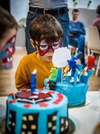 Close-up of a boy with spider man face paint an a birthday cake