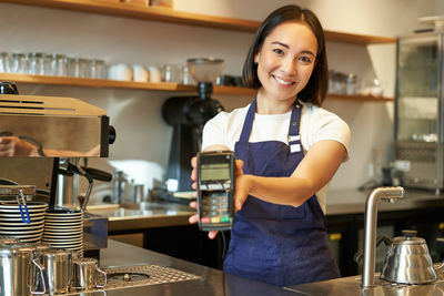 Portrait of smiling young woman standing in cafe