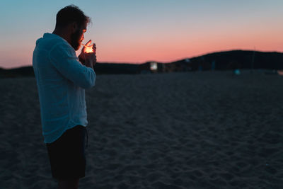 Man standing on beach against sky during sunset