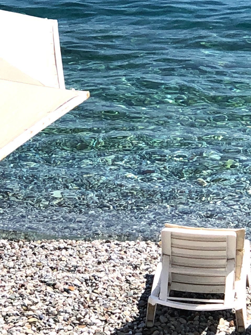 HIGH ANGLE VIEW OF EMPTY CHAIR AT BEACH