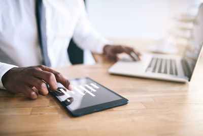 Midsection of man using mobile phone on table