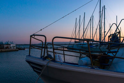 Sailboats moored in sea against sky at sunset