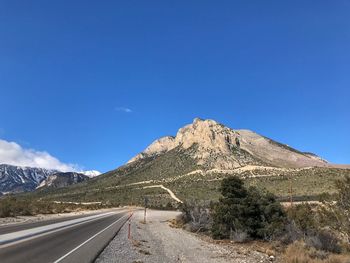 Road by mountain against blue sky