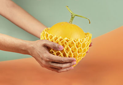Close-up of hand holding fruit against white background