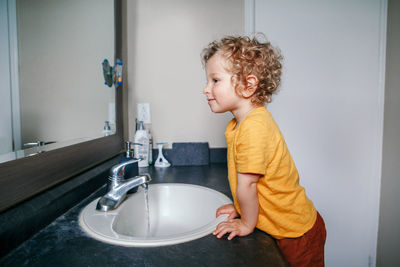Boy toddler washing hands in bathroom at home. health hygiene and morning routine for children. 