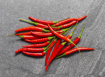 Several fresh red hot chili pepper on a dark black stone background food ingredient concept 