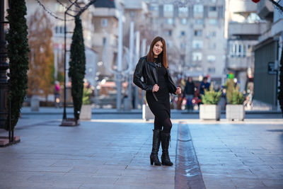 Full length portrait of young woman in city