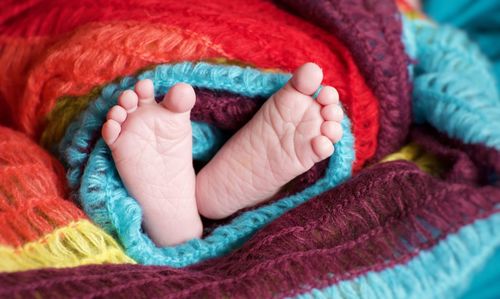 Close-up of baby wrapped in woolen blanket on bed