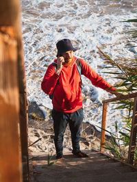 Bearded millennial man in red hoody backpack autumn sea dry reed authentic hipster tourist lifestyle