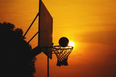 Low angle view of basketball hoop against orange sky