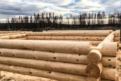 Stack of wood on field against sky