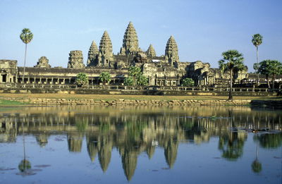 Angkor wat temple reflecting in lake against sky