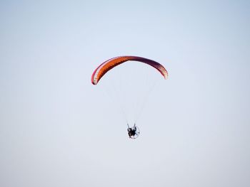 Low angle view of person paragliding against clear sky