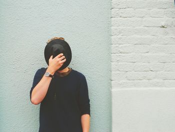 Young man standing against white wall