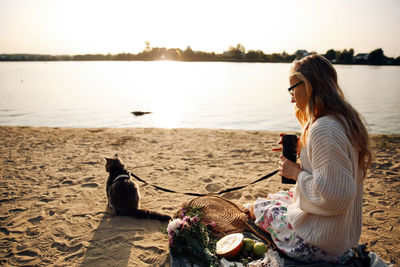 Woman using smart phone while sitting on beach