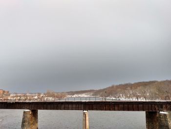 Bridge over river in city against sky