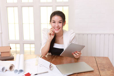 Portrait of young woman using phone while sitting on table