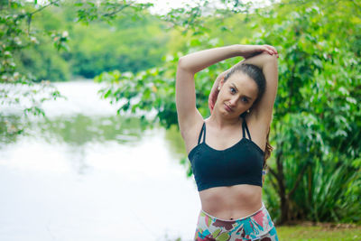 Portrait of smiling beautiful woman exercising against trees