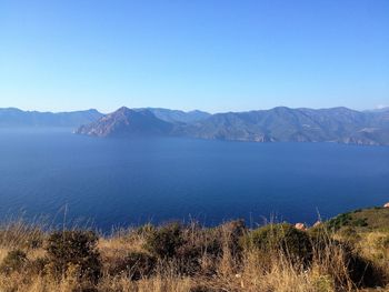 Scenic view of lake and mountains against clear blue sky