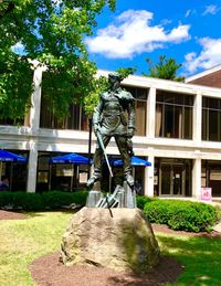 Statue against trees and building against sky