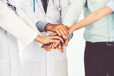 Midsection of doctors stacking hands