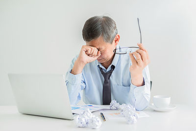 Stressed mature businessman sitting at desk in office