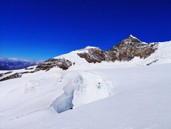 Scenic view of snowcapped mountains against clear blue sky