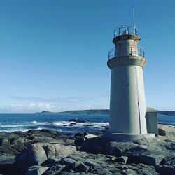 Lighthouse by sea against sky