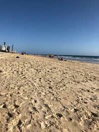 People on beach against clear sky