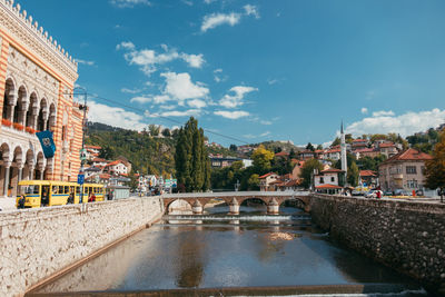 Bridge over river in city against sky