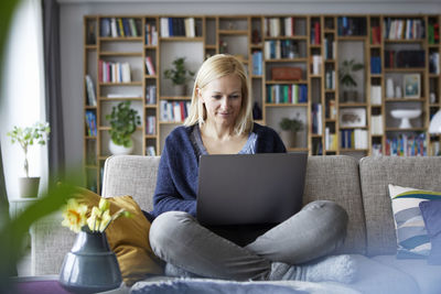 Woman at home sitting on couch using laptop