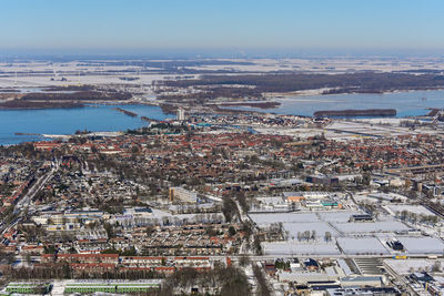 High angle view of illuminated city by sea against sky