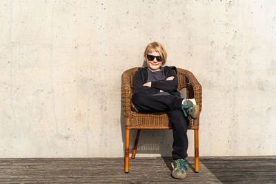 Portrait of young woman sitting against wall