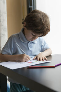 Boy drawing on paper at home