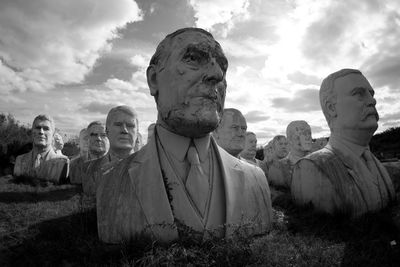 Statues on field against sky