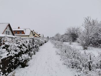 Snow covered houses and trees against clear sky