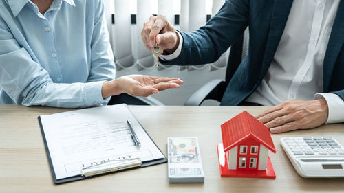 Midsection of real estate agent and customer shaking hands in office