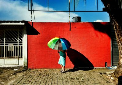 Rear view of man walking on red umbrella