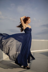 Young woman wearing blue dress while standing on building terrace