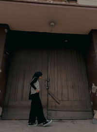 Side view of a woman standing in front of the old building door