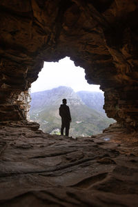 Rear view of man standing in cave