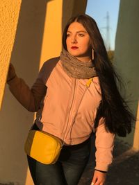 Thoughtful young woman standing against columns during sunset