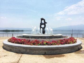 View of fountain by lake against sky