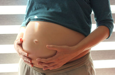 Midsection of woman touching mirror