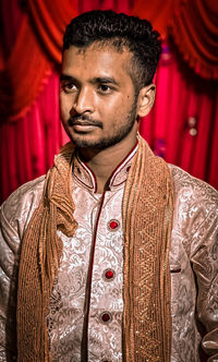 Young man standing against curtain