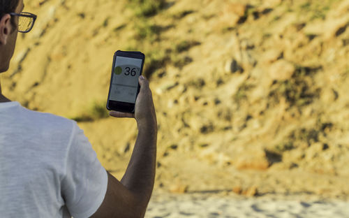 Rear view of man using mobile phone at remote location