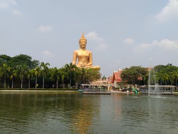 Statue by water against sky