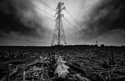 Electricity pylon on field against sky